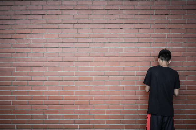 back view teenage asian boy standing front red brick wall background 43448 69