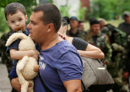2jun2014 homem leva seu filho durante tiroteio entre militantes pro russia e guardas que defendem a fronteira em luhansk no leste da ucrania 1401726844062 956x500
